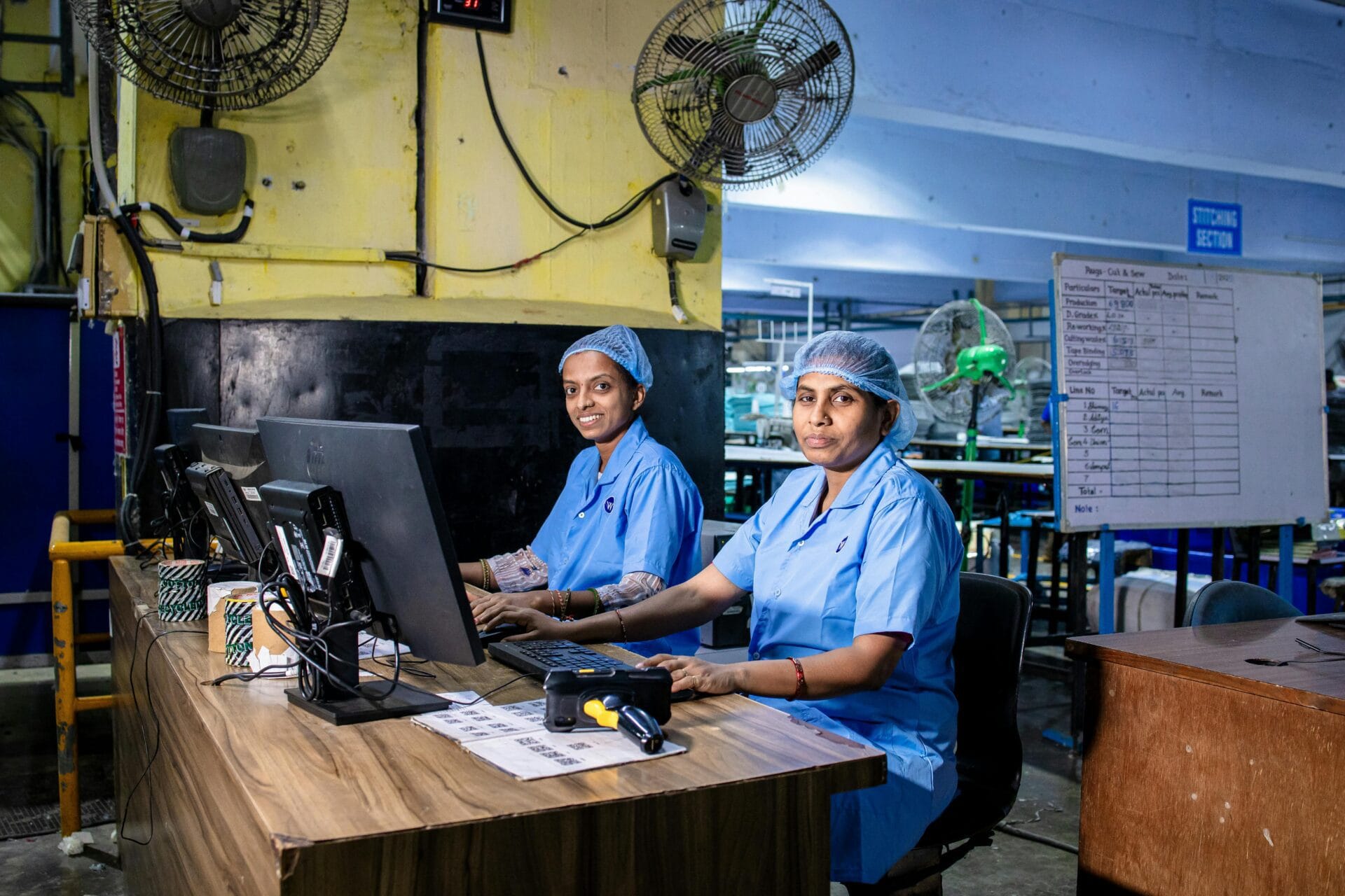 Indian blue-collar textile workers using computers in a factory setting.